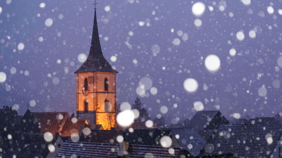Schneeflocken vor der nächtlichen Kirche in Muttenz.