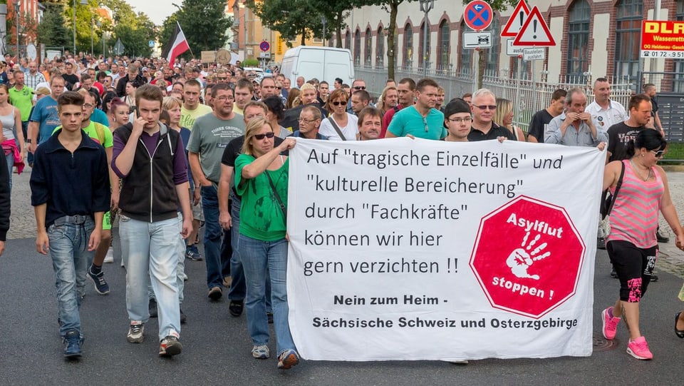 Demonstranten in Heidenau tragen ein asylkritisches Transparent vor sich her. 