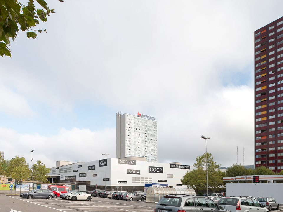 Parkplatz mit Autos. Rechts und im Hintergrund Hochhäuser