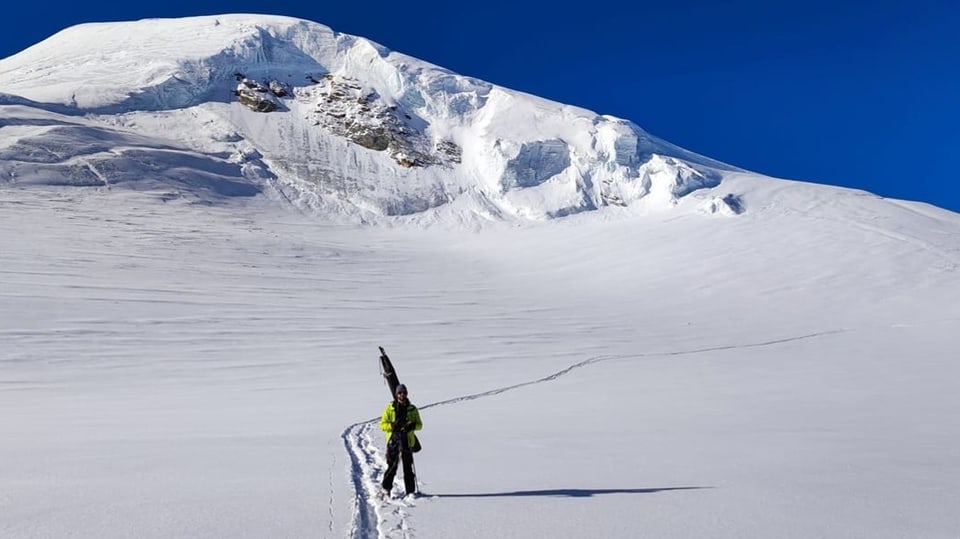 Mann läuft in einem Trampelpfad auf einer riesigen Schneefläche
