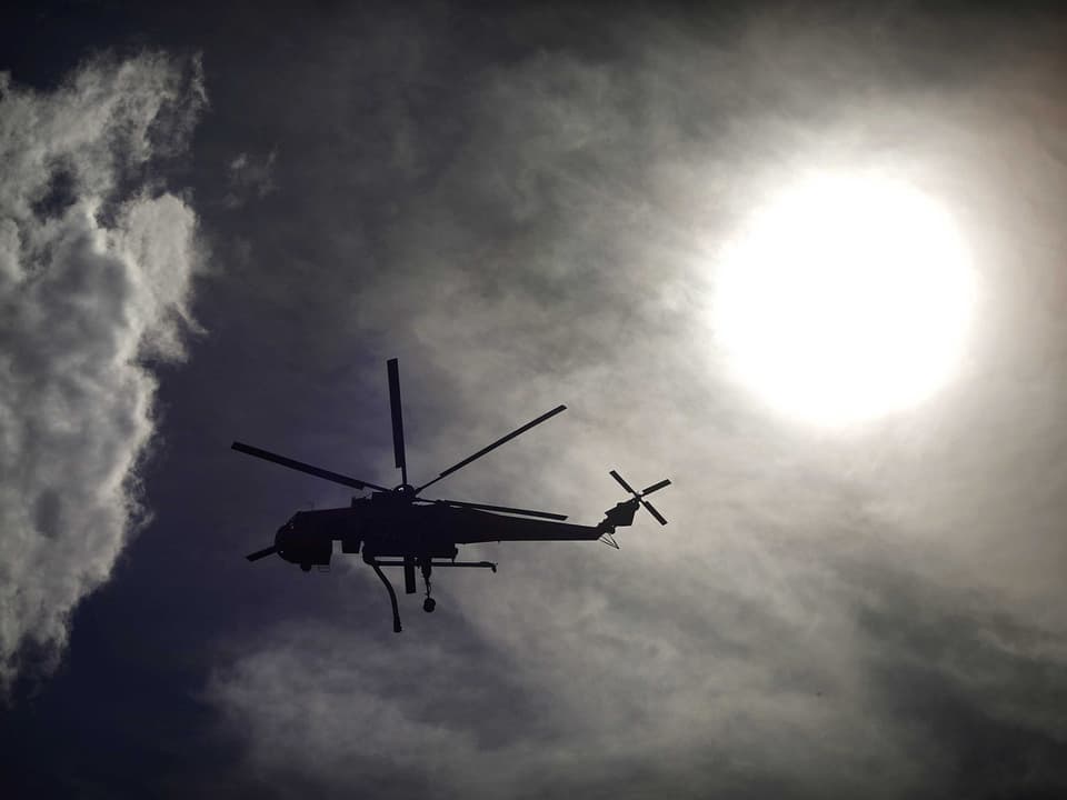 Lösch-Helikopter an einem rauchverhangenen Himmel.
