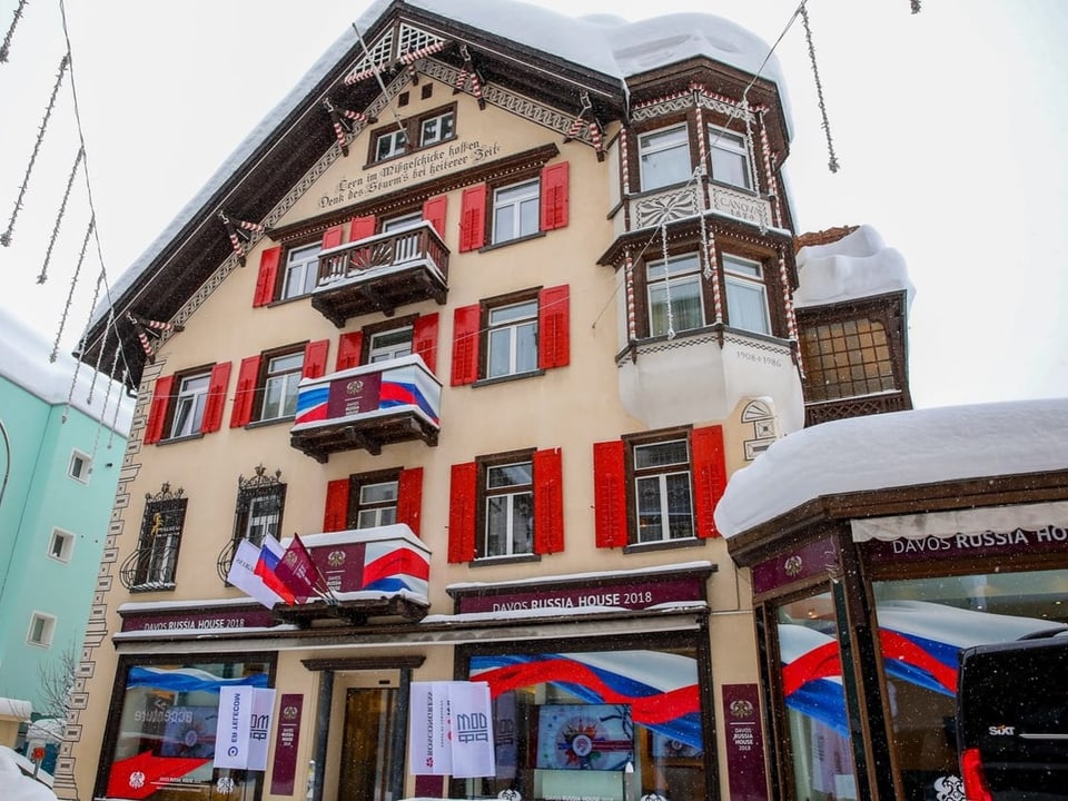 Ein verschneites Haus in Davos. Teile der Fassade sind mit russischen Flaggen geschmückt.