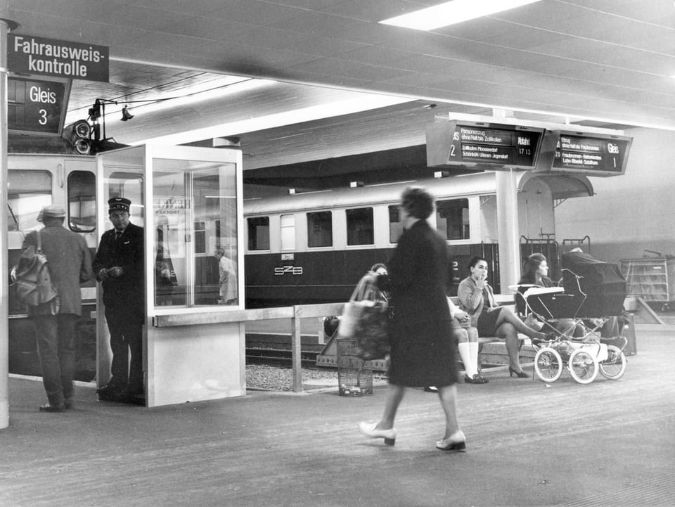 Schwarz-weiss-Bild: U-Bahnhof mit Billetkontrolleur in einem Häuschen und davor eine Frau auf einer Bank sitzend mit Kinderwagen