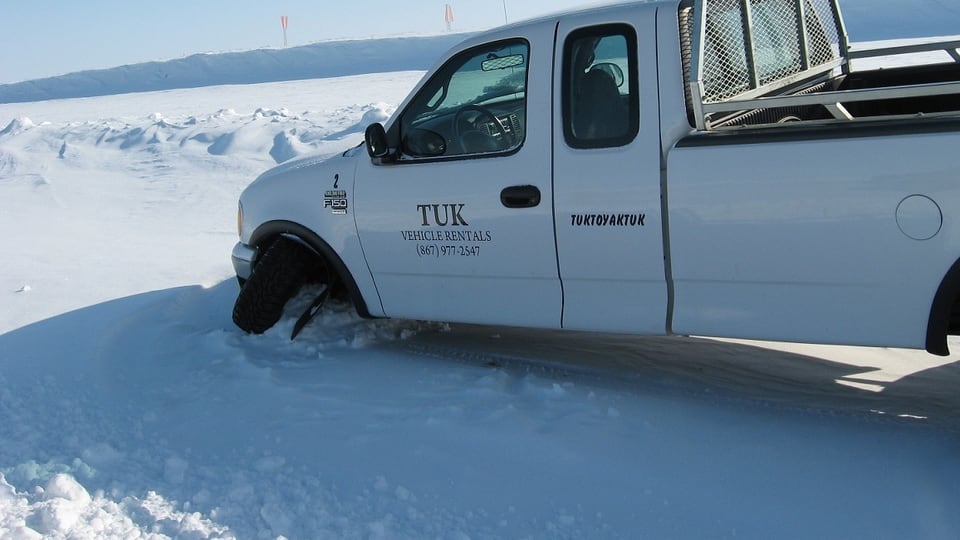 Ein weisser Truck ist im Schnee eingeklemmt.