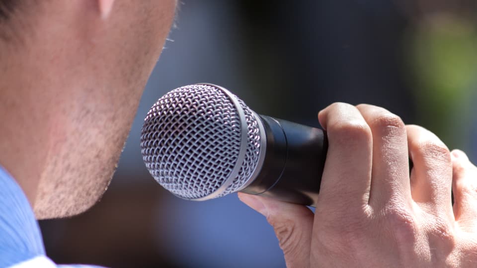 Ein Mann hält ein Mikrofon.