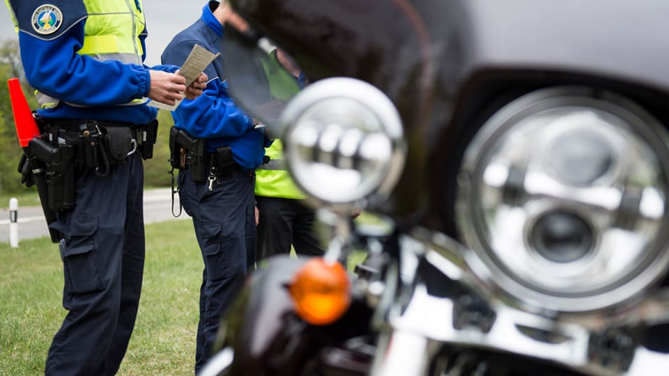 Polizisten vor einem Motorrad.