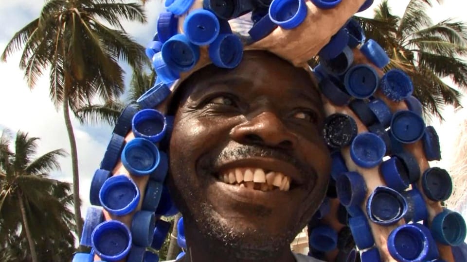 Afrikaner auf Lamu präsentiert einen aus Petflaschen-Deckeln gefertigen Hut.