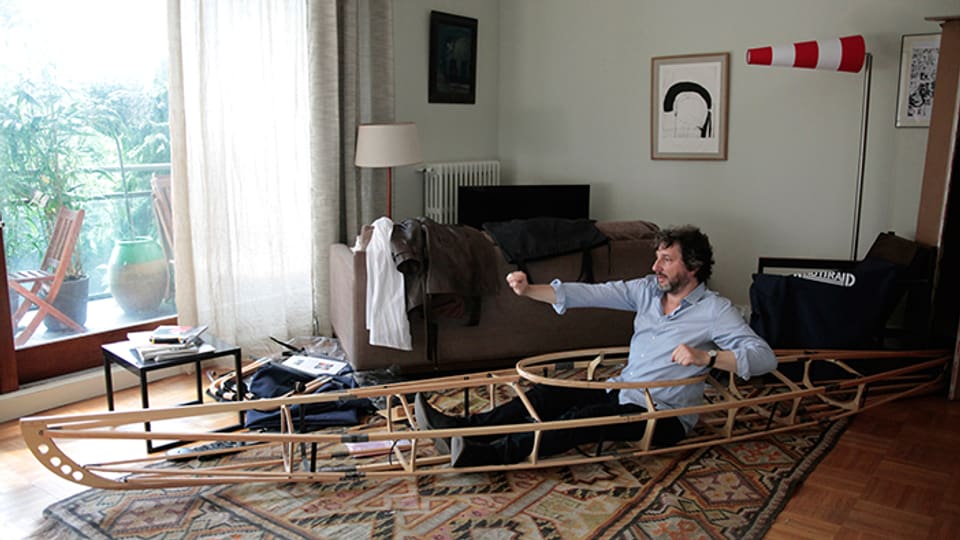 Ein Mann paddelt in einem Kajak-Gerüst in seinem Wohnzimmer vor sich hin.