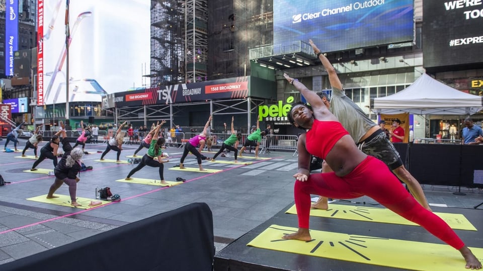Viele Menschen machen Yoga-Übungen auf dem Time Square in New York.