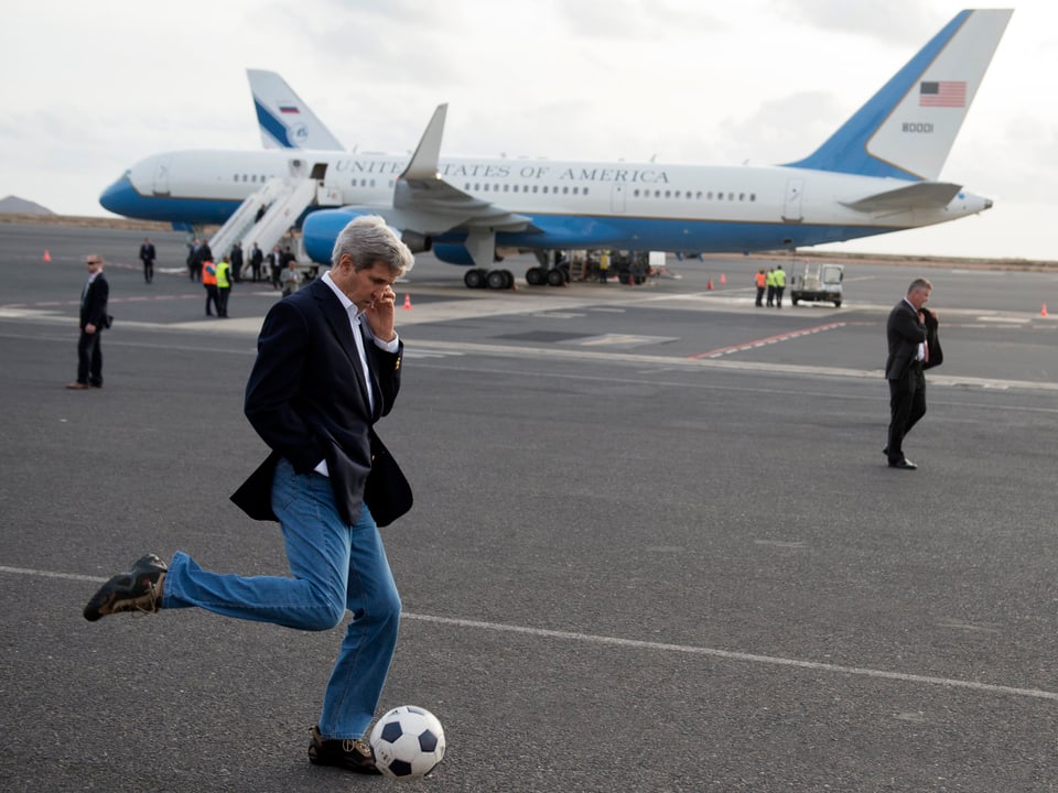 John Kerry spielt Fussball neben dem Flugzeug. 