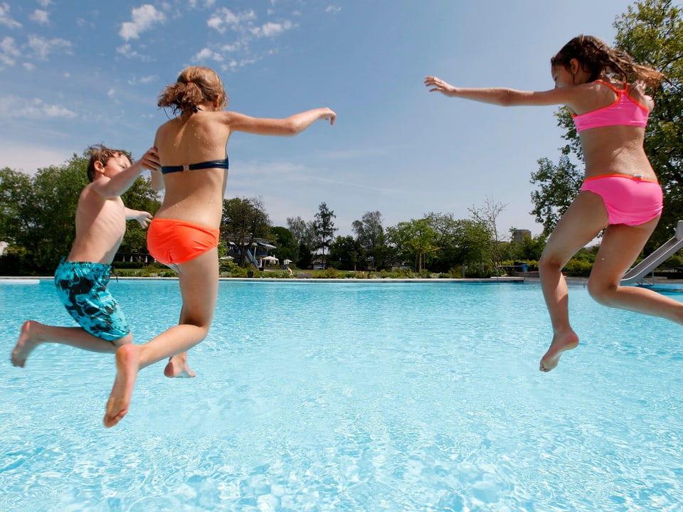 Drei Kinder springen in ein Schwimmbad.
