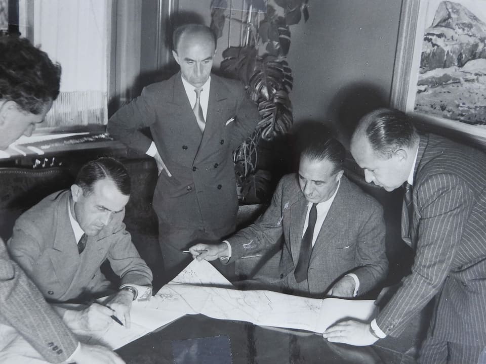 Auf einem historischen Foto unterzeichnen Männer ein Dokument.