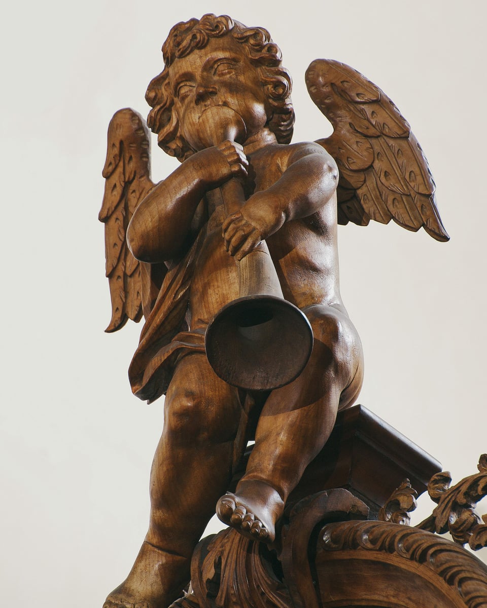 Ein Engel aus Holz mit Posaune.