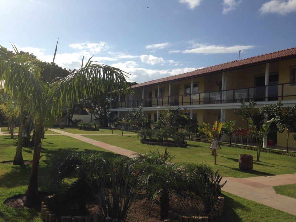 Innenhof eines Hotelkomplexes mit Palmen und Rasen.