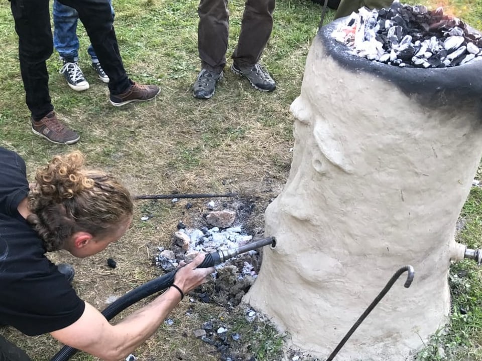 Mann steckt Schlauch in Ofen.