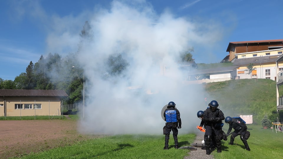 Polizisten vor einer Rauchwolke.