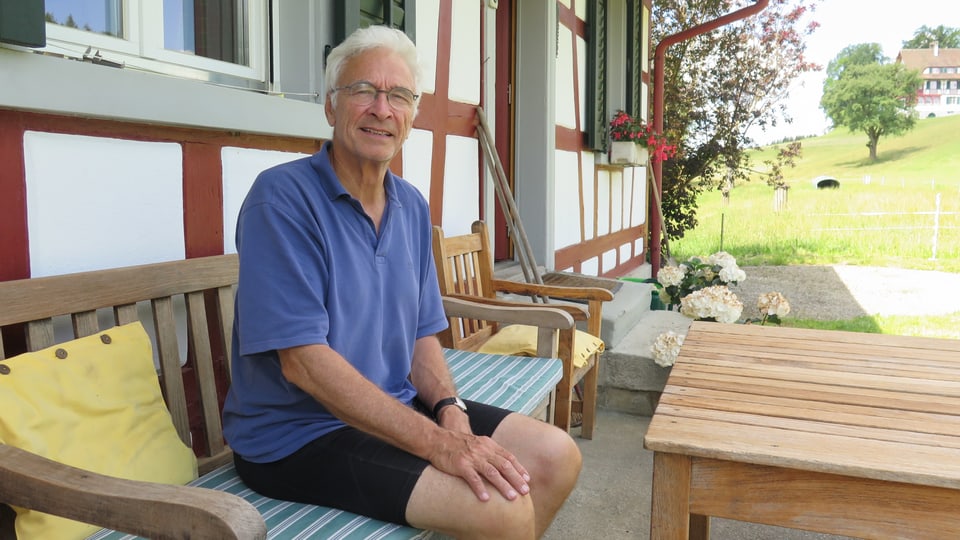 Seniore Hubert Lombard sitzt vor seinem Bauernhaus. 
