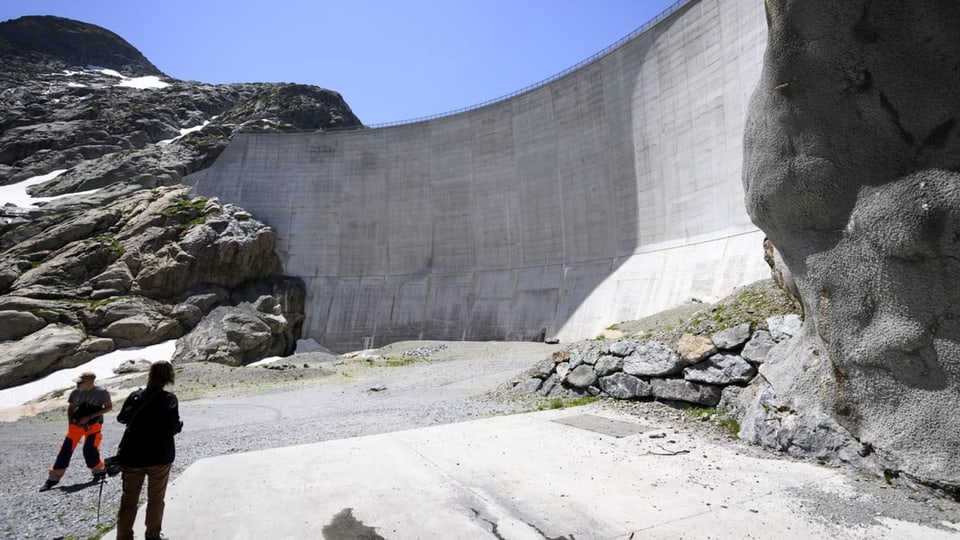 Eine Staudammmauer mit Menschen davor