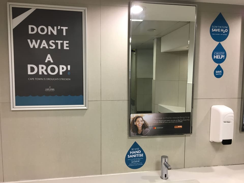 Plakate 'Don't waste a drop' hängen im öffentlichen WC.