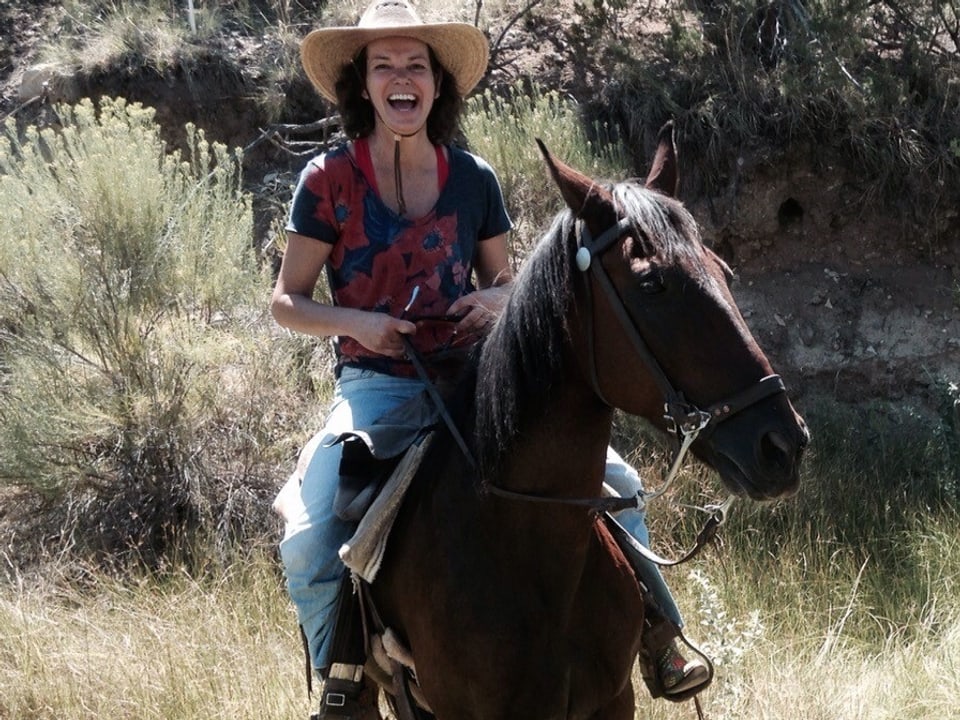 Milena Moser mit Cowboyhut auf einem Pferd.
