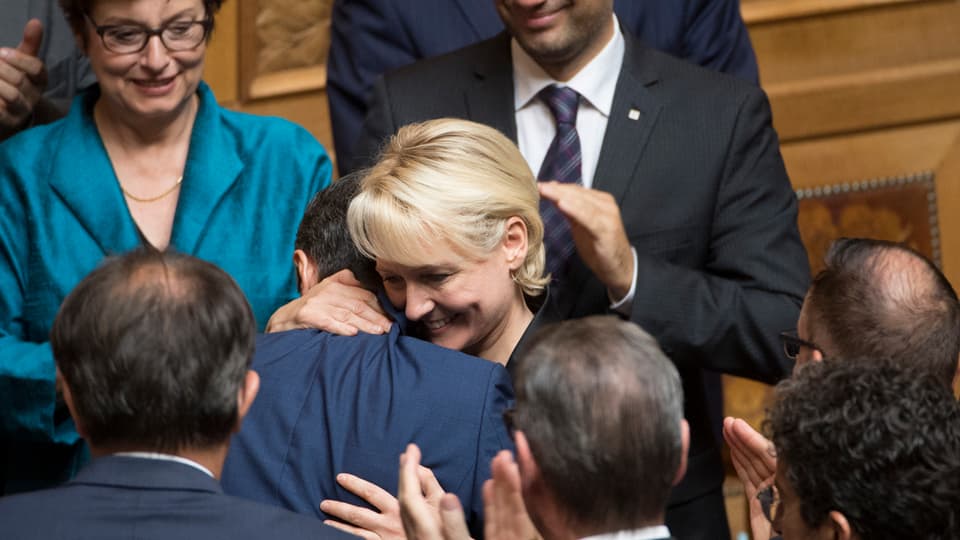 Moret umarmt Cassis von applaudierenden Parlamentariern umgeben.