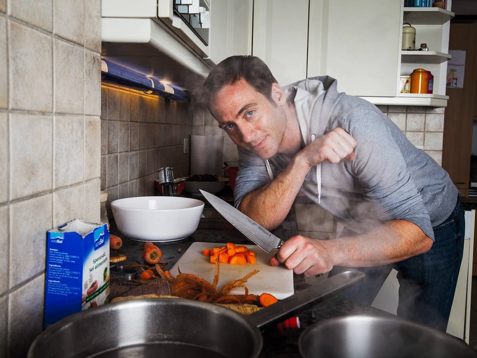 Elias schneidet Karotten mit seinem Lieblingsmesser und posiert in der Küche für die Kamera.