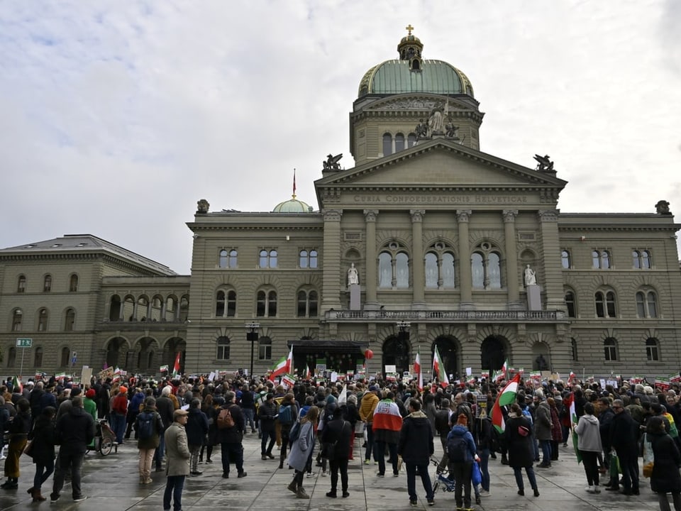 Eine Menschenmenge steht auf dem Bundesplatz in Bern. Sie halten Iran-Flaggen. Im Hintergrund das Bundeshaus.