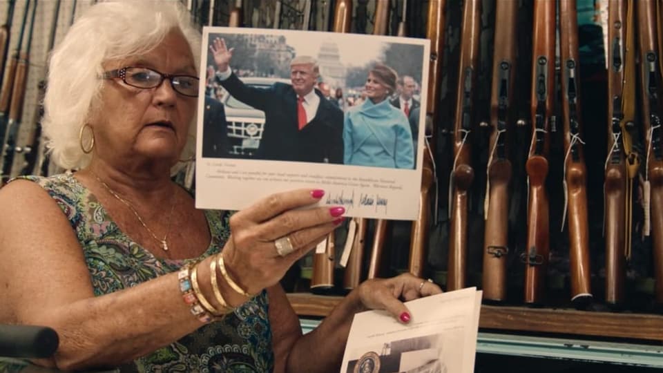 Waffenladenbesitzerin Linda Vernon hält Bild von Donald und Melania Trump vor Waffenwand 