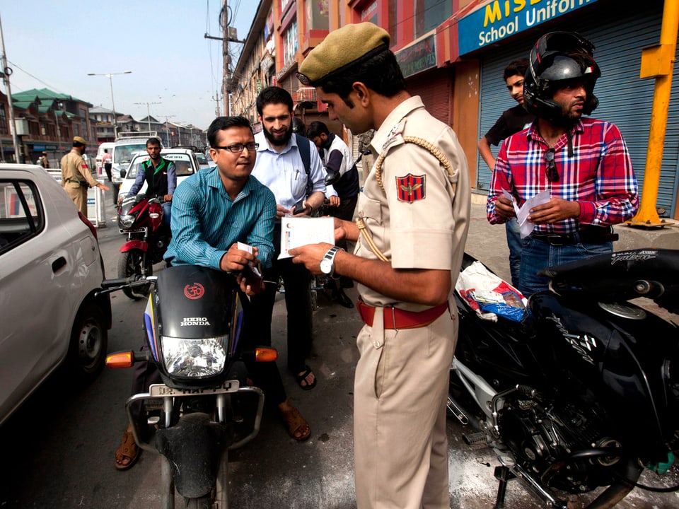 Ein indischer Polizist kontrolliert die Papiere von Motorradfahrern.