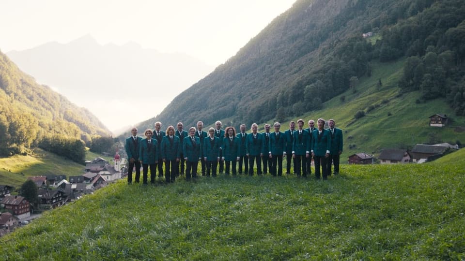 Chor in grünen Uniformen steht mitten in einer Berglandschaft