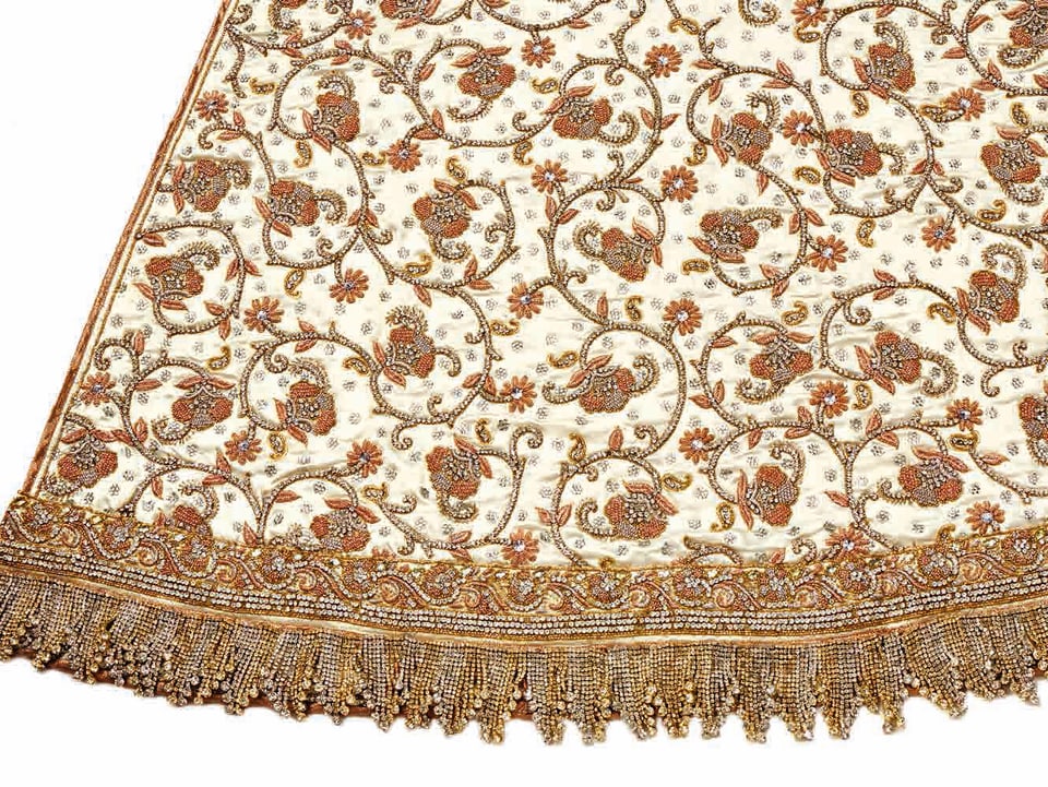Nahaufnahme des Utara-Kleids: weisser Stoff mit geschwungenen, im indischen Stil aufgeführten Verzierungen mit Swarowski-Bordüre.