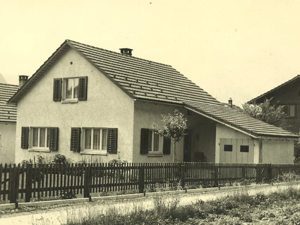 Schwarz-Weiss-Fotografie von einem Zweifamilienhaus mit Garten.