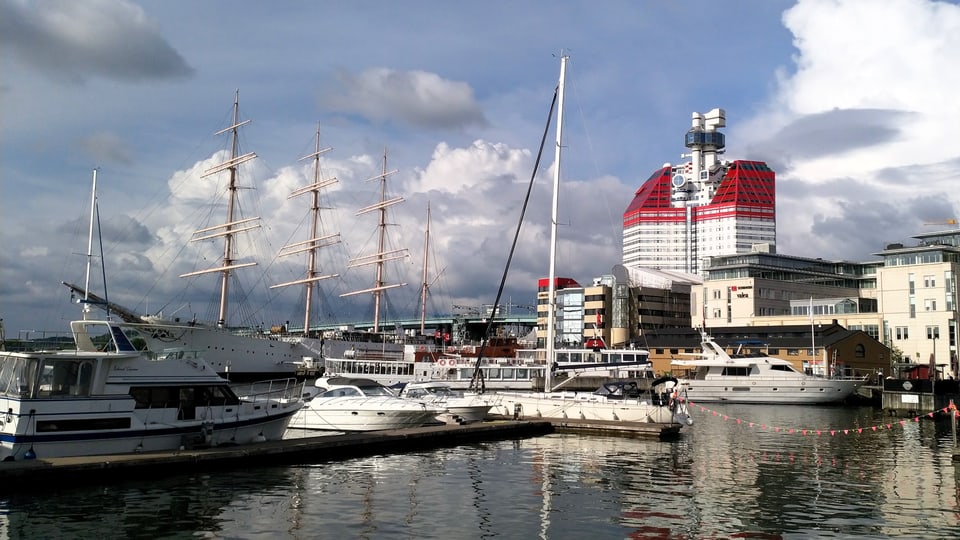 Schiffe im Hafen, Im Hintergrund ein hohes, modernes Gebäude.