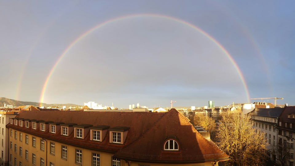 Ein Regenbogen über den Dächern der Stadt.