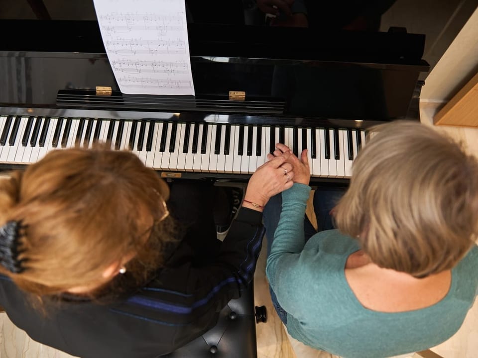Zwei Frauen mittleren Alters spielen gemeinsam Klavier