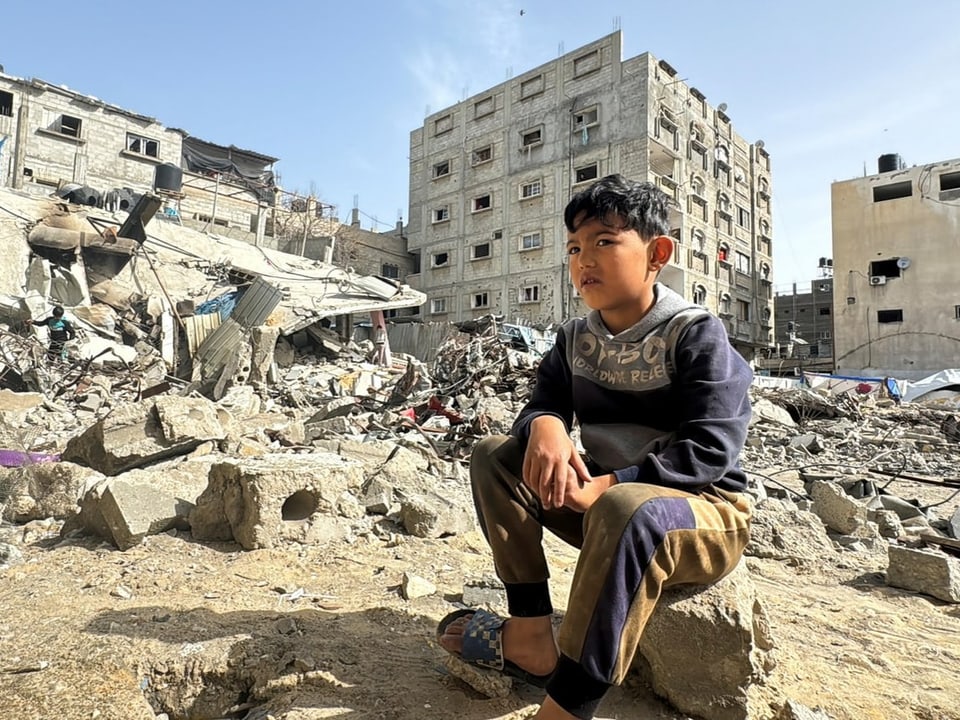 Ein palästinensischer Junge sitzt neben den Ruinen eines zerbombten Hauses in Rafah.