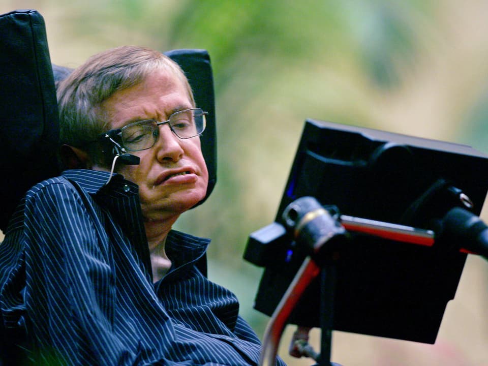 Der britische Astrophysiker Stephen Hawking in seinem Rollstuhl, der ihn mit einem Bildschirm auch bei der Kommunikation unterstützt.