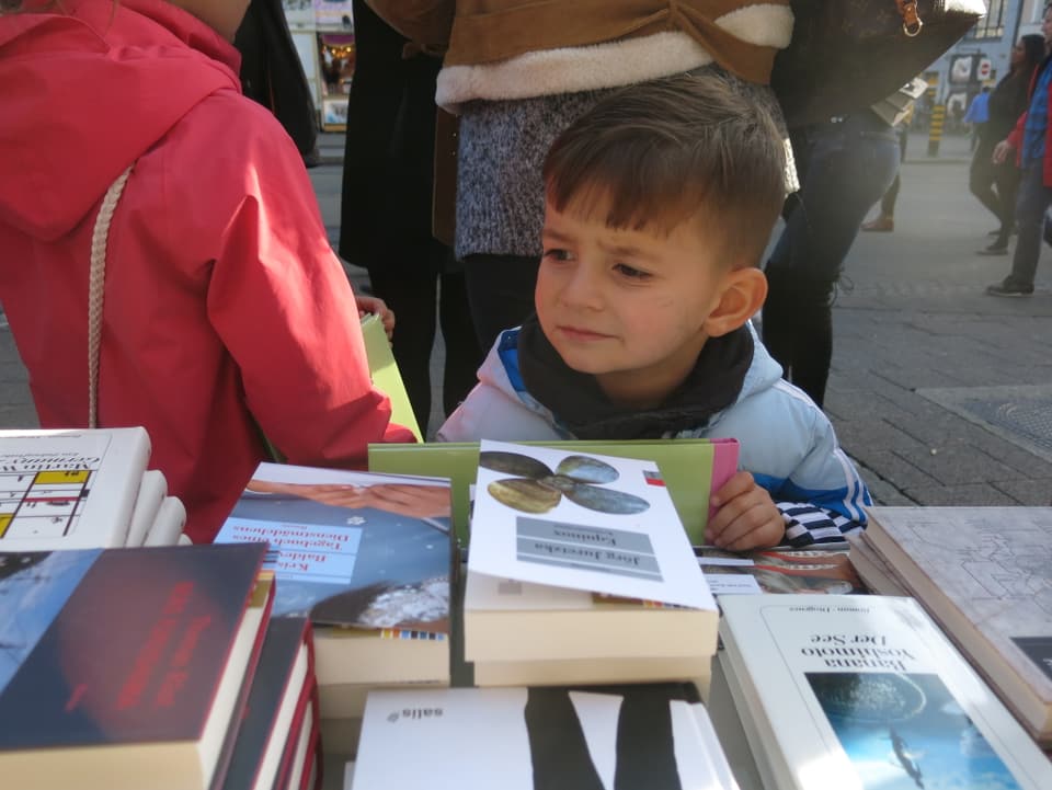 Nahaufnahme eines kleinen Jungen, der sich Bücher ansieht.