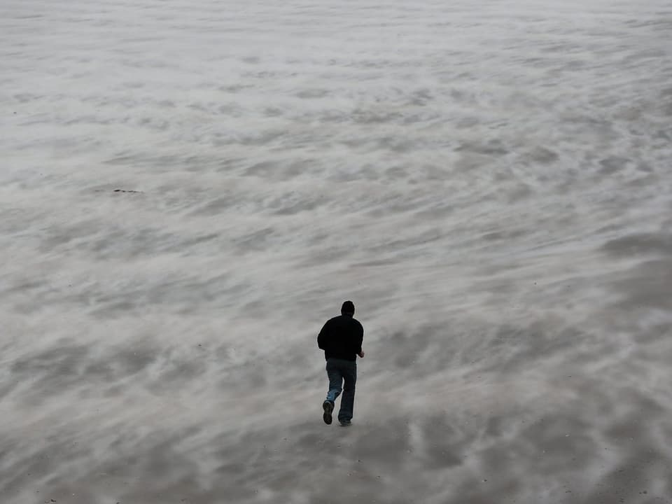 5.12.2013 Ein Mann läuft in Blankenberge (Belgien) über den aufgewühlten Sand. 