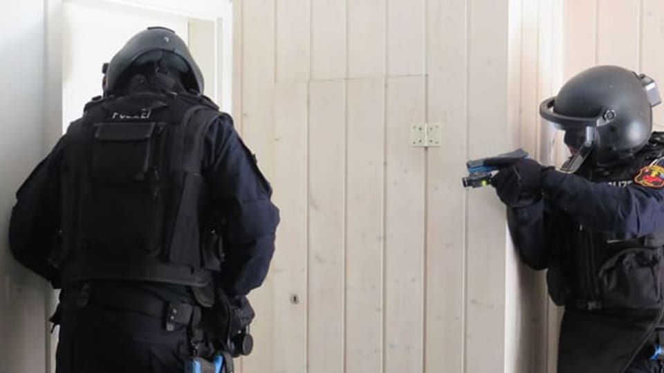 Zwei Polizisten in Vollmontur an einer Türe mit Waffen
