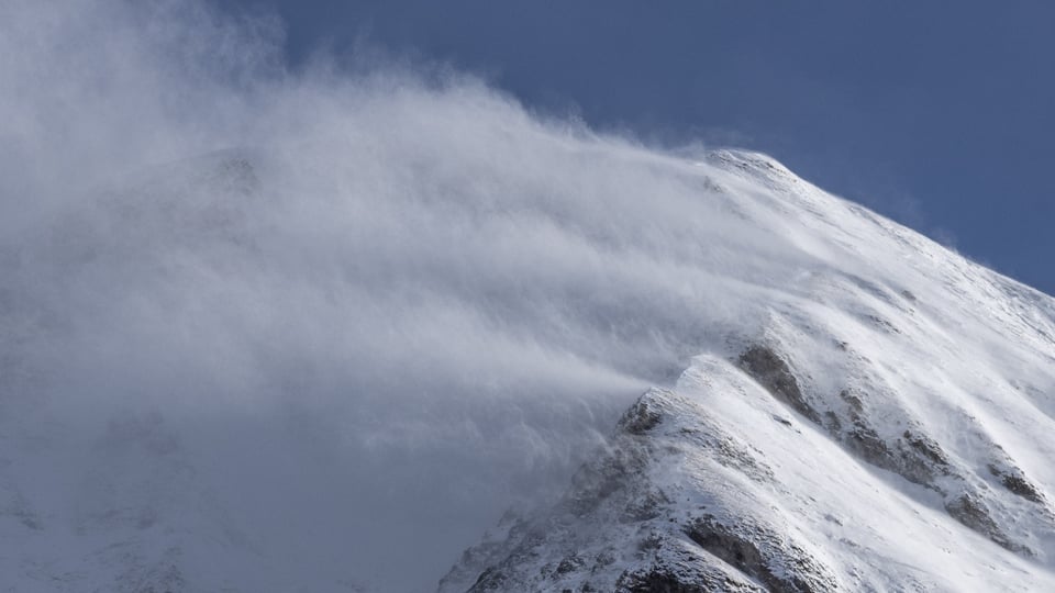 Föhnsturm Schnee wird über einen Bergkamm geblasen.
