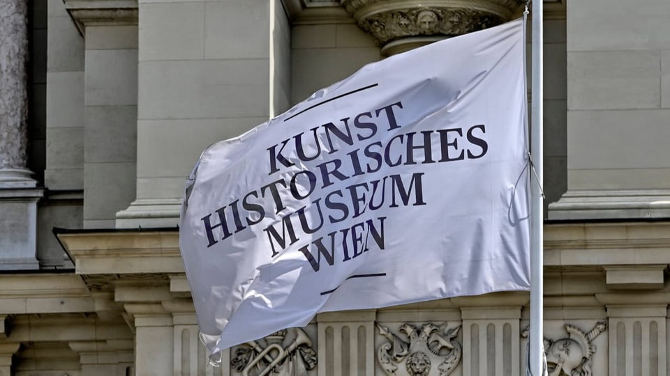 Eine Fahne weht vor einem altehrwürdigen Gebäude mit der Aufschrift: Kunsthistorisches Museum Wien.