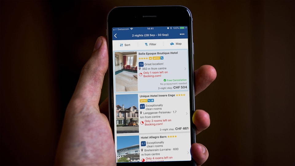 Ein Smartphone-Bildschirm zeigt Suchresultate der Seite Booking.com an.