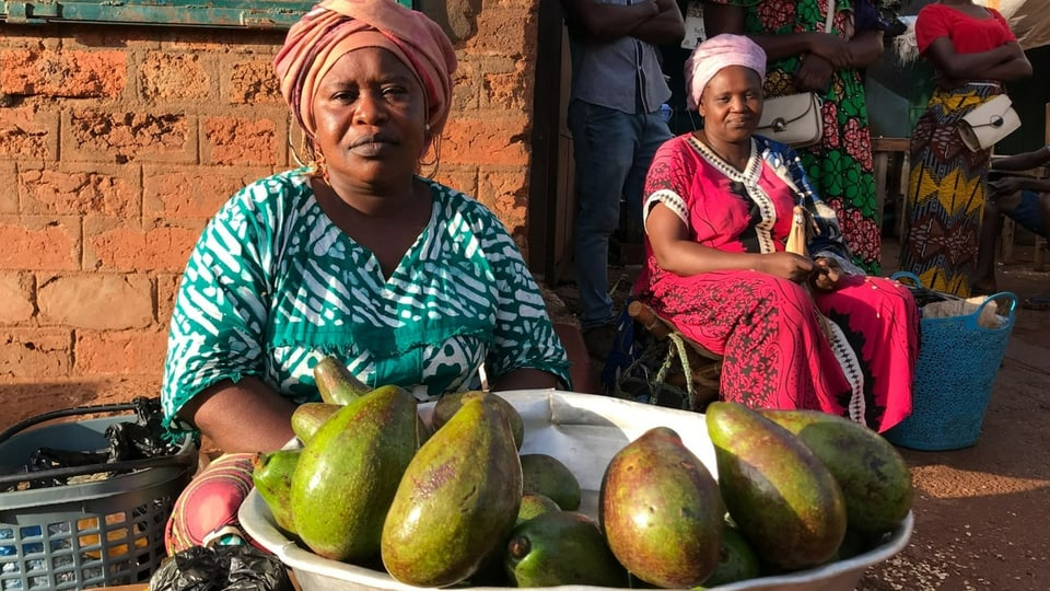 Verkäuferin sitzt vor einer Schale mit Avocados