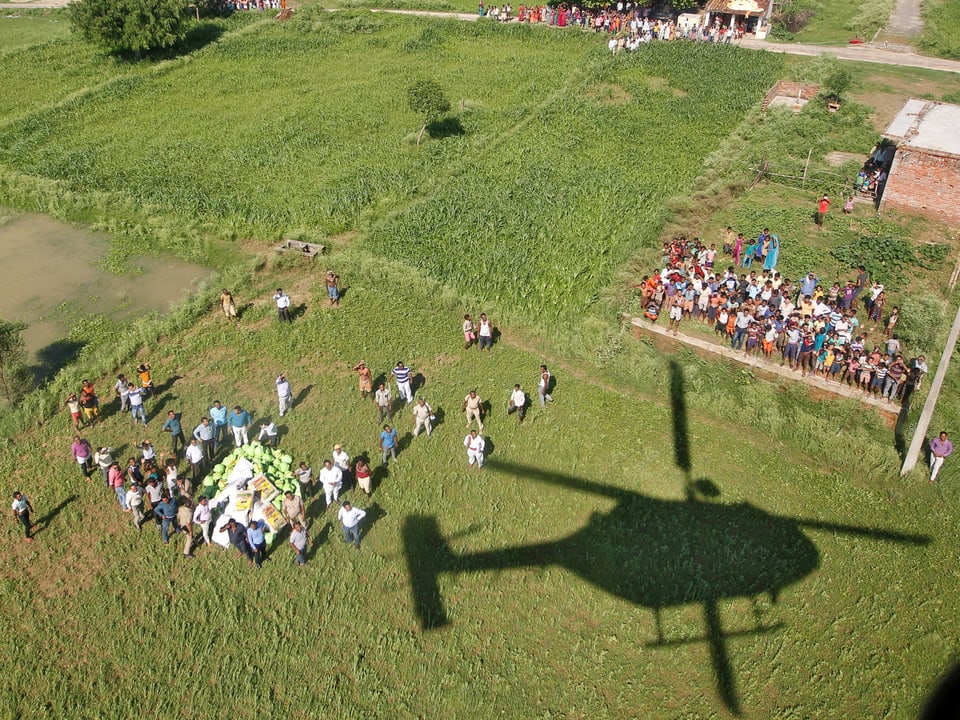 Silhouette eines Helikopters auf einem Feld nachdem er Lebensmittel abgeladen hat aus der Luft fotografiert