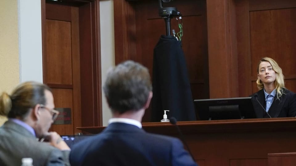 Johnny Depp hört seiner Ex-Frau Amber Heard zu Gerichtssaal zwei Männer von hinten, eine Frau von vorne erhöht