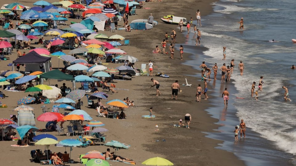 Viele Sonnenschirme und Badende am Strand von Malaga.