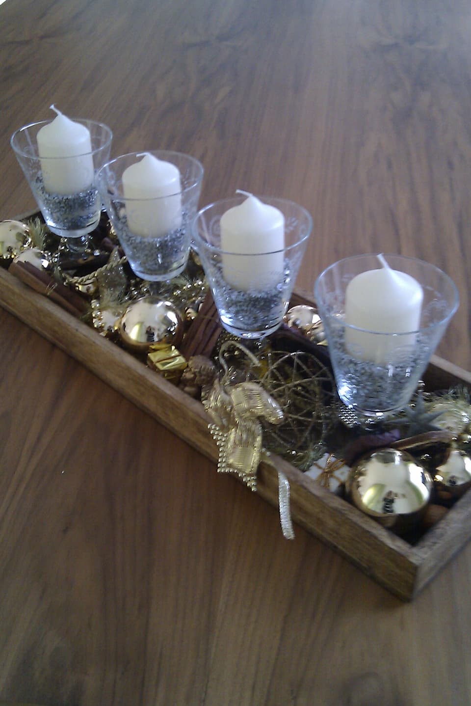 Alte Weingläser mit Kerzen stehen auf einem Holztablett.