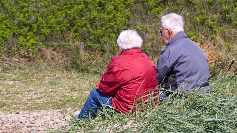 Zwei Rentner hocken im Gras.