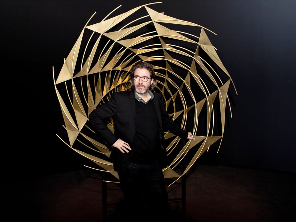 Olafur Eliasson steht vor einem goldenen Spirale.